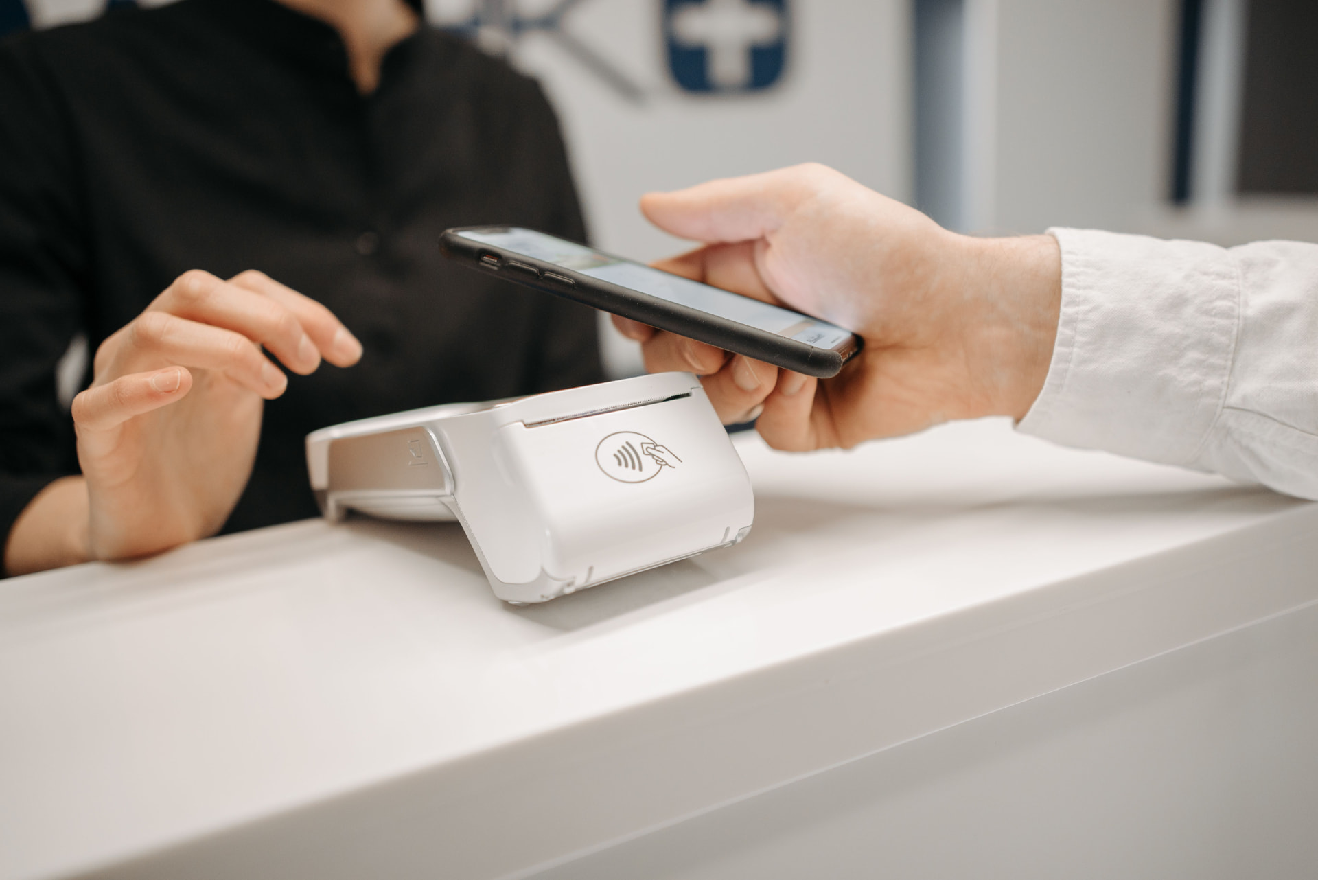 Customer paying by phone on a contactless card terminal at the counter